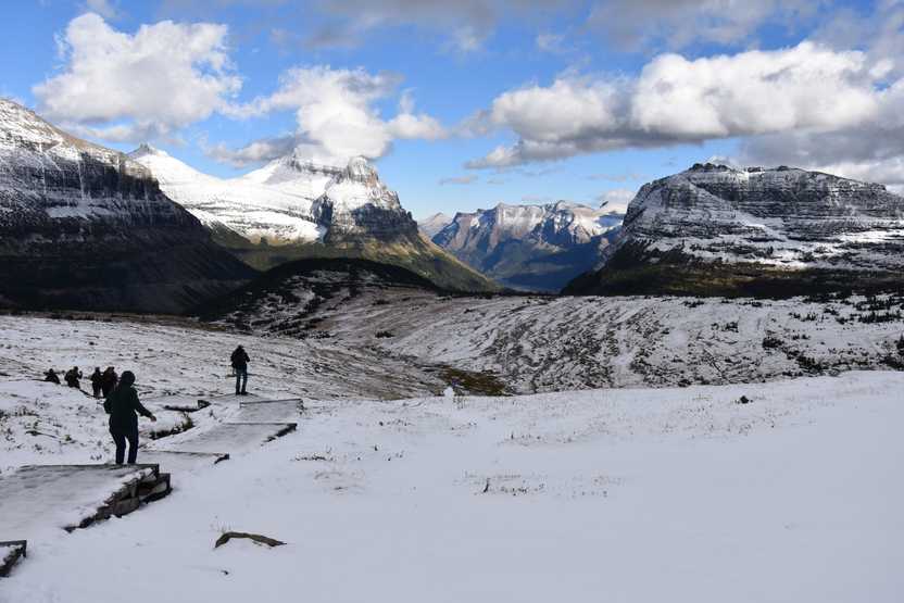 A snowy scene with people hiking on icy steps inside of Glacier National Park