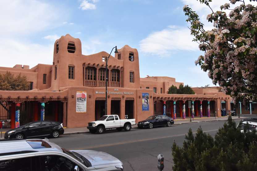 The exterior of the Museum of Contemporary Native Arts. There are overhangs with colorful columns on the sidewalks leading to the entrance.
