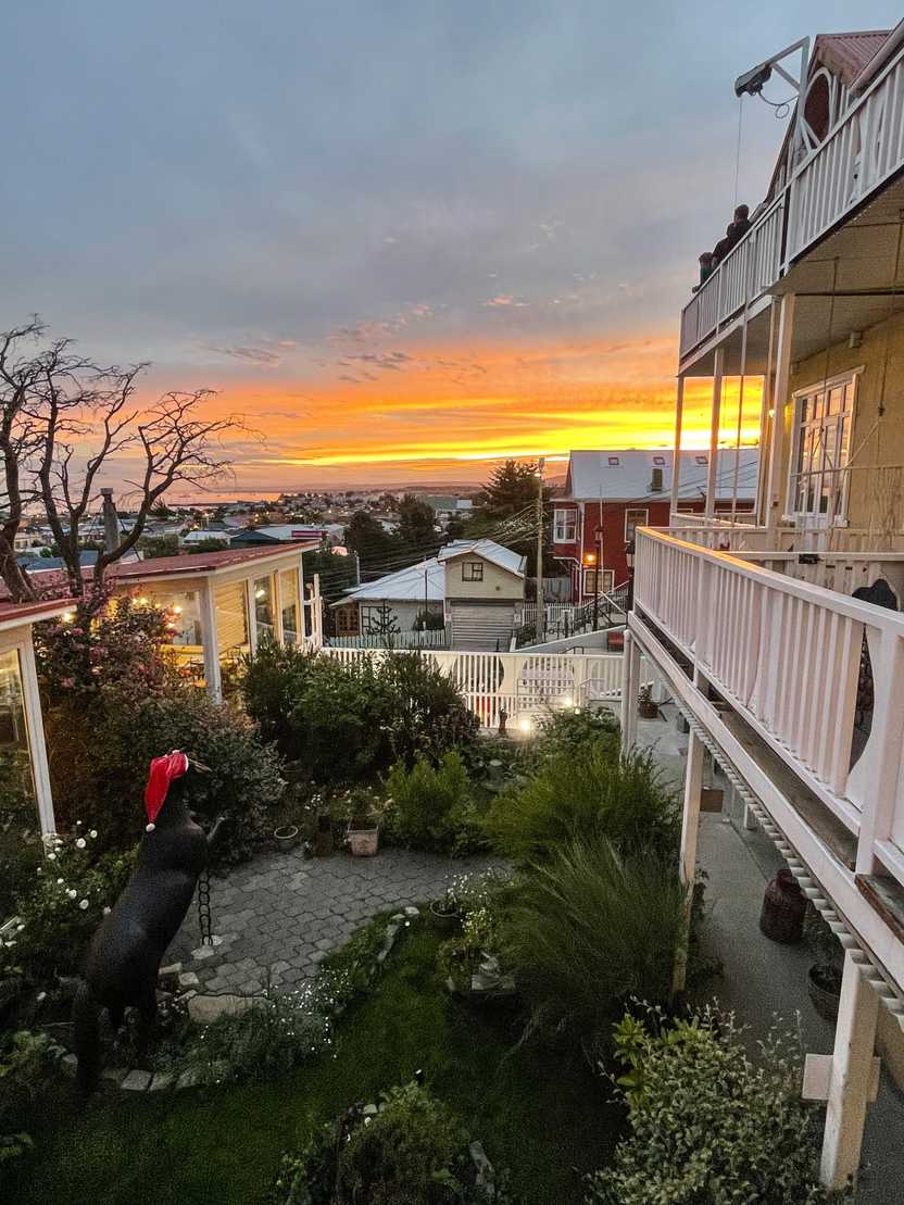 A sunset sky seen from the backcony of Hotel La Yegua Loca. The sky glows orange and there is a courtyard below with a horse statue wearing a santa hat.