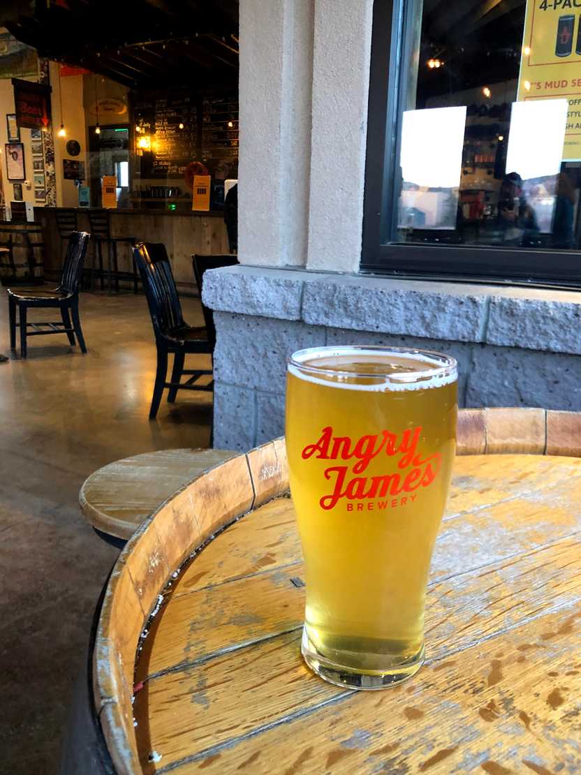 A golden colored beer sitting on a barrel in Angry James Brewery. A golden colored beer sitting on a barrel in Angry James Brewery.