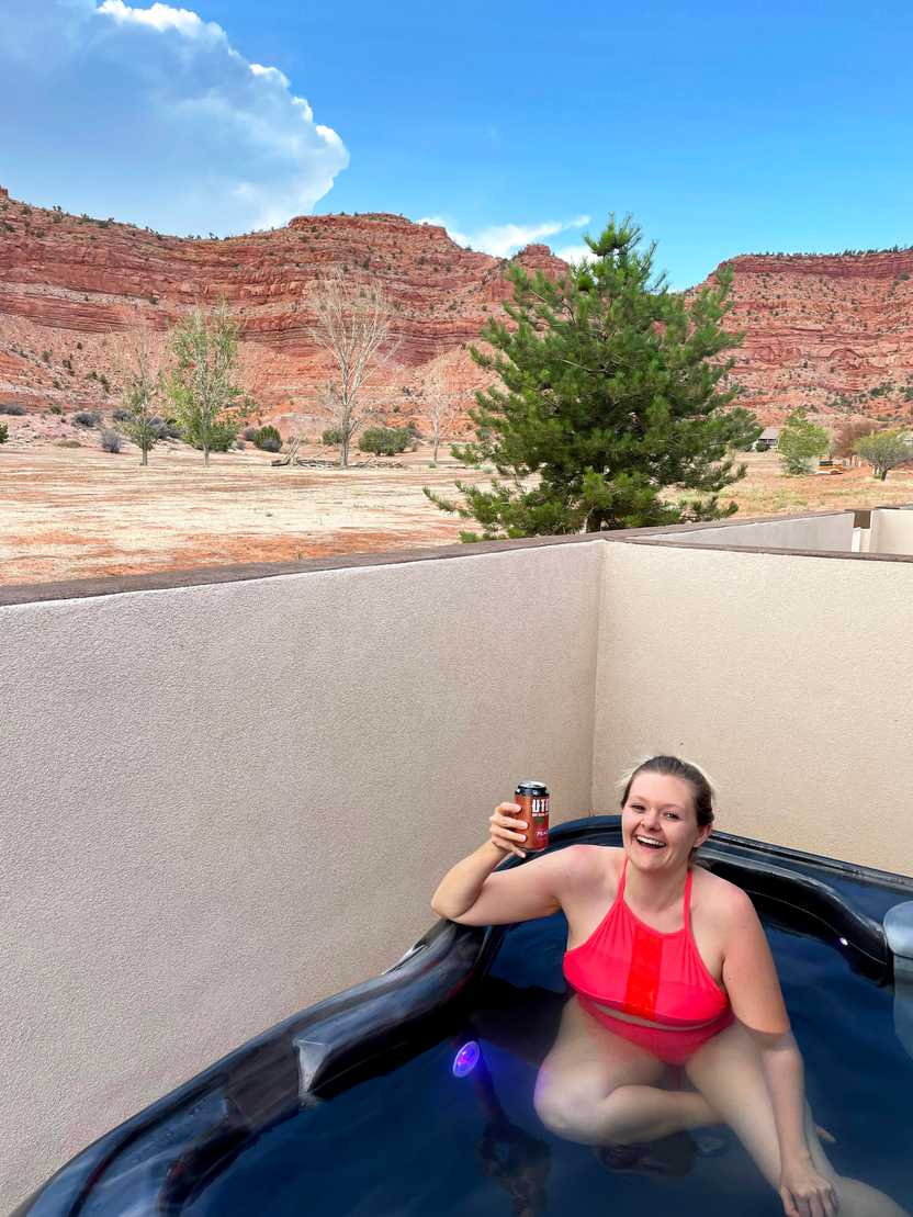 Lydia in a hot tub with views of orange mountains in the background. Lydia in a hot tub with views of orange mountains in the background.