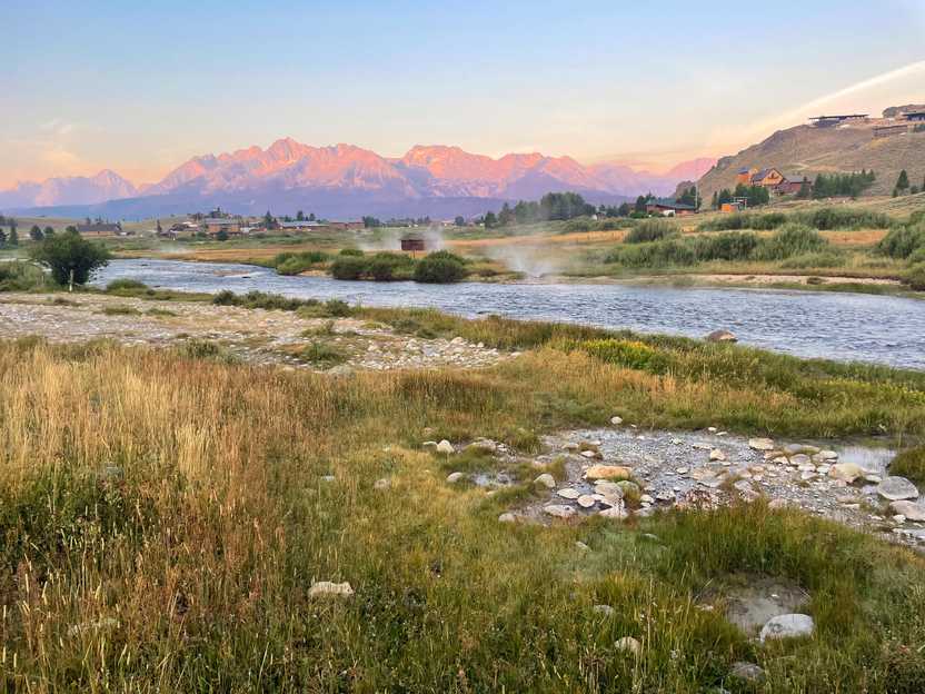 Looking at Valley Creek with the mountains in the distance during sunrise. The mountains are pink due to the light.