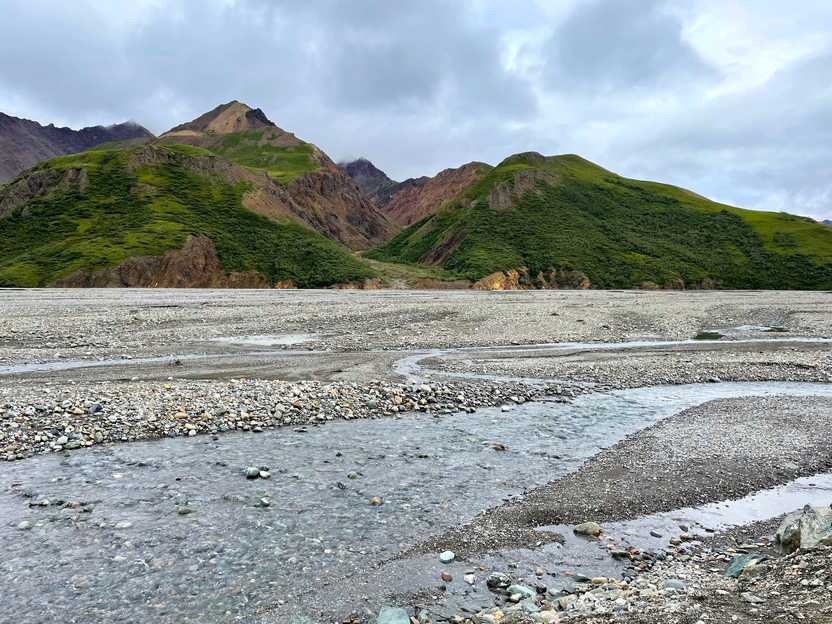 A expansive river wash area with green mountains across the wash.