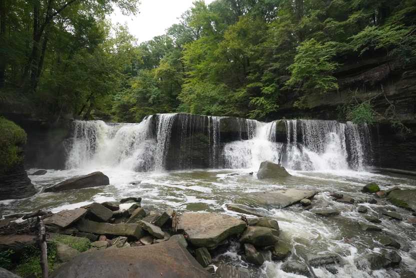 Looking straight at a large waterfall that goes across a river.
