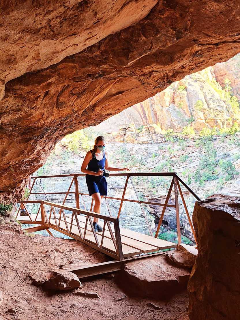 Lydia hiking on a wooden bridge under a rock overhang on the Canyon Overlook Trail in Zion National Park. Lydia hiking on a wooden bridge under a rock overhang on the Canyon Overlook Trail in Zion National Park.