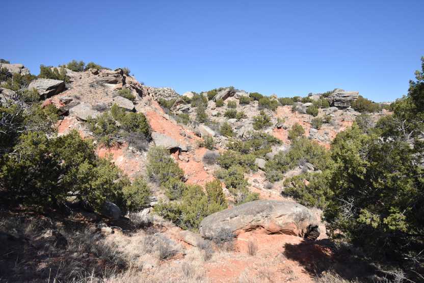 A pile of orange rocks with green bushes scattered around on the Rock Garden Trail.