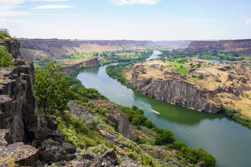 A view looking down at the Snake River with a few people paddling on the water.