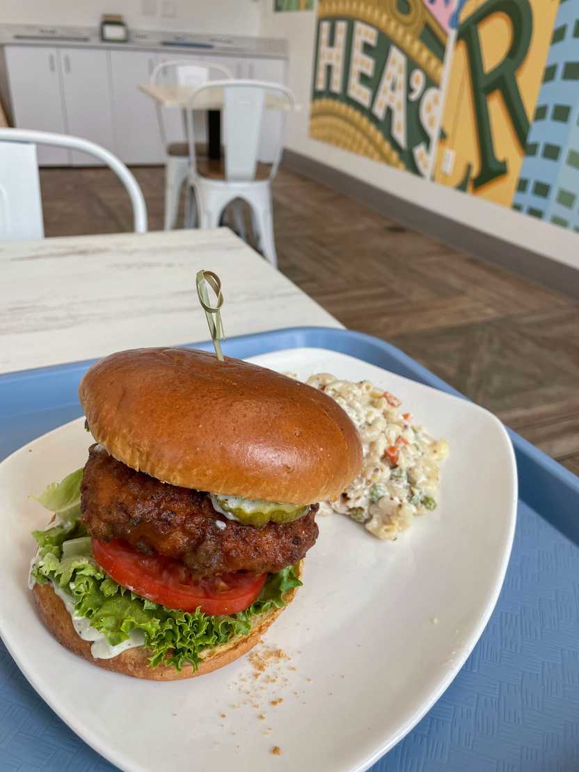 A vegan buffalo chicken sandwich served with macaroni.