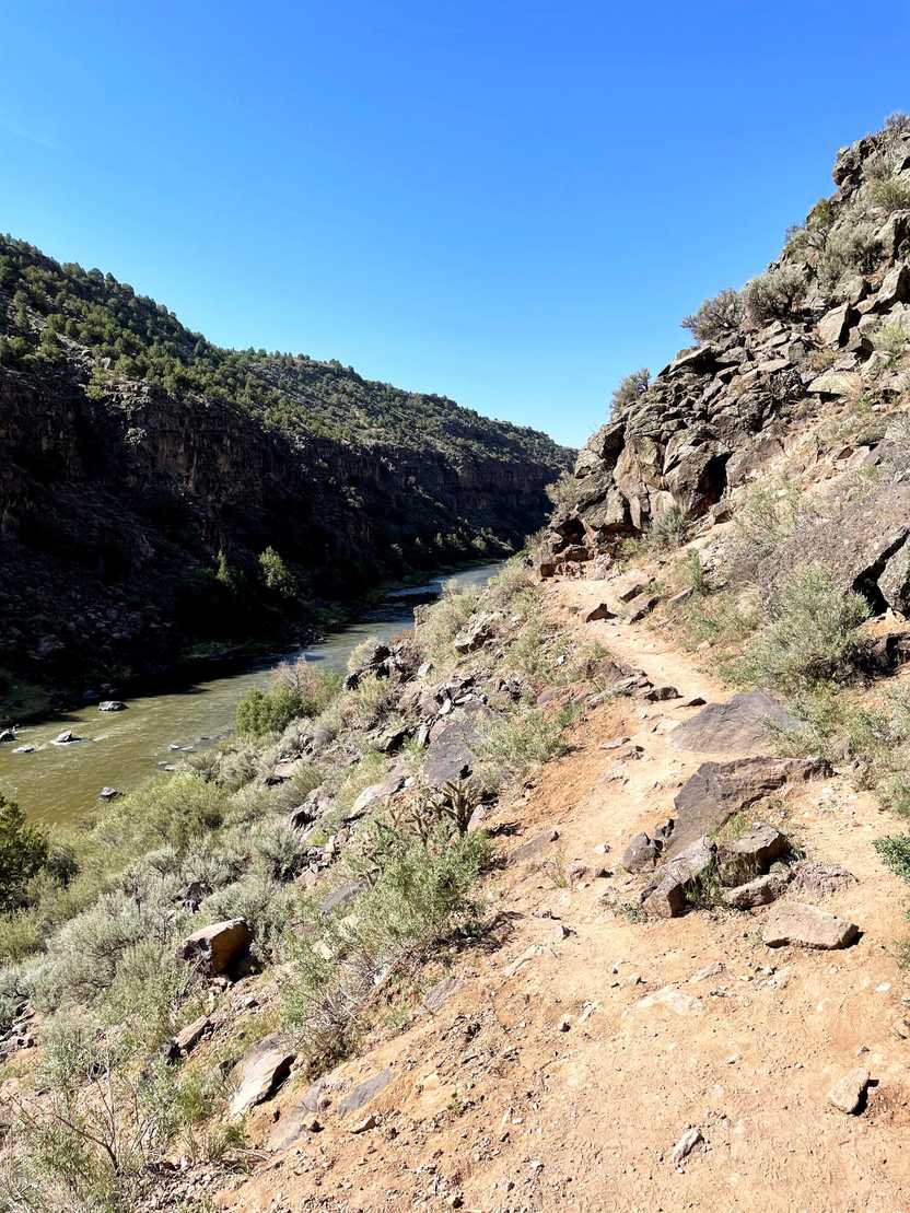 A trail leading along the mountain with a view of the river down below.
