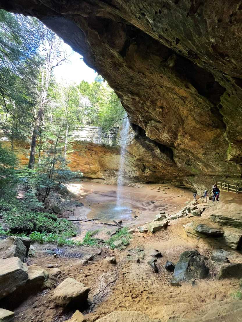 A view of Ash Cave and a waterfall coming from the top from the side.