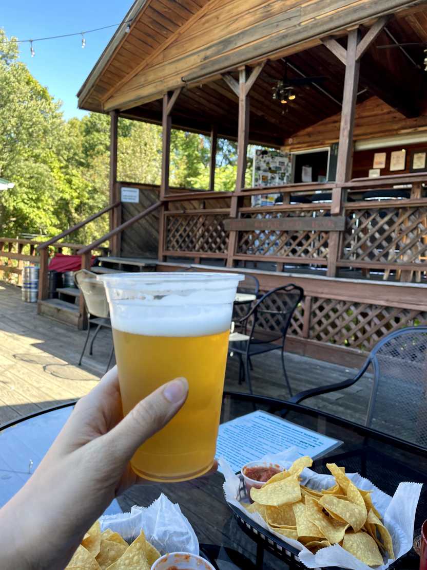 Holding up a beer the Burrito Bar at Breeze Hill. There are tortilla chips on the table.