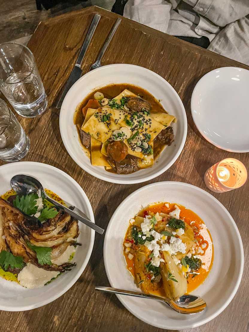 Three small plates from The Little Club. There is a ravioli plate, a cauliflower plate and a plate with vegetables and an orange sauce.