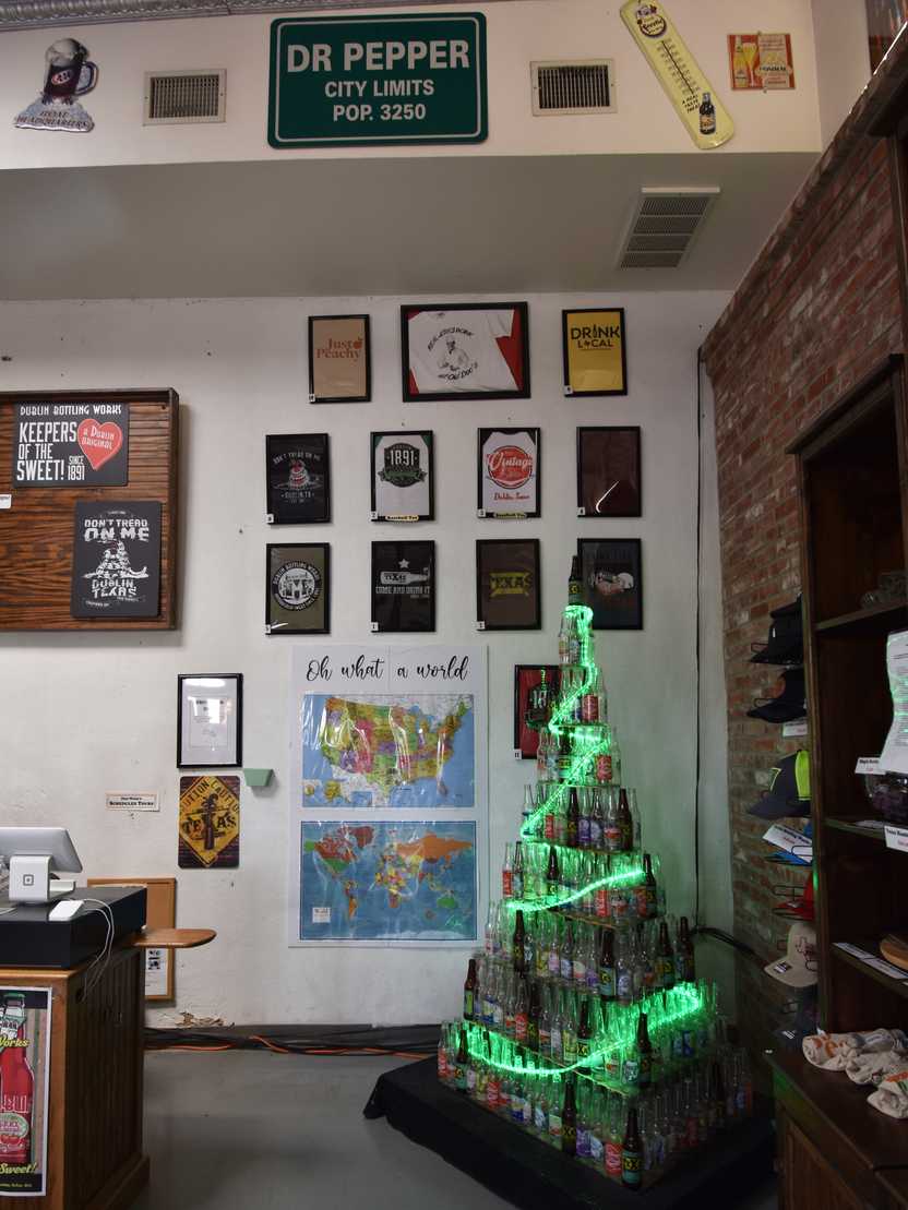 A pyramid of bottles that resemble a Christmass tree, with green lights going around the tower.