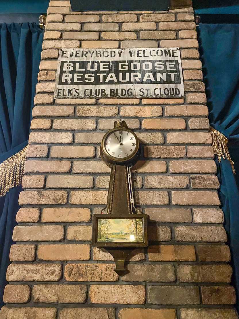 A clock and a vintage-looking sign on a brick wall in the Blue Goose Speakeasy A clock and a vintage-looking sign on a brick wall in the Blue Goose Speakeasy