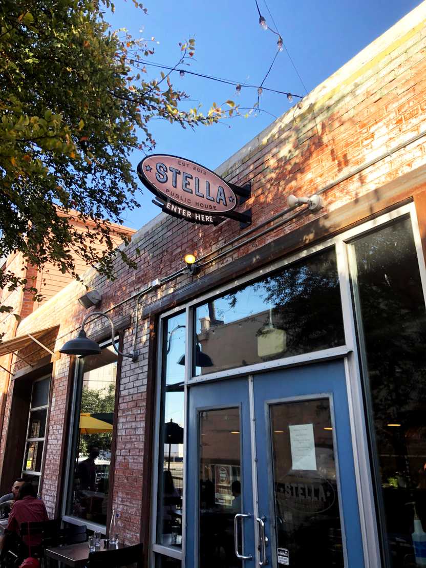 The exterior of Stella Public House. There is a brick building with a blue door.