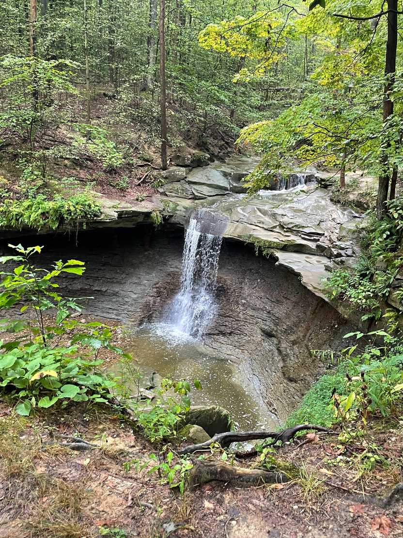 Looking down at a small waterfall flowing over a cave.