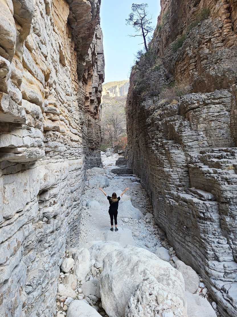 Lydia standing with her back to the camera in the Devil's Hall. There are towering walls on either side.