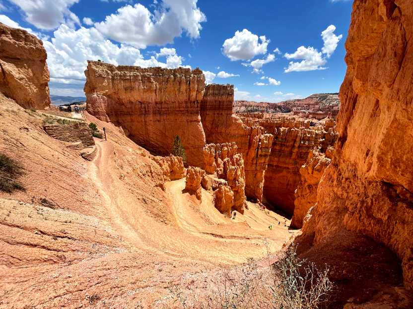 An area of swithbacks leading to the bottom of the canyon in Bryce Canyon. The switchbacks are framed by tall, orange rock formations.