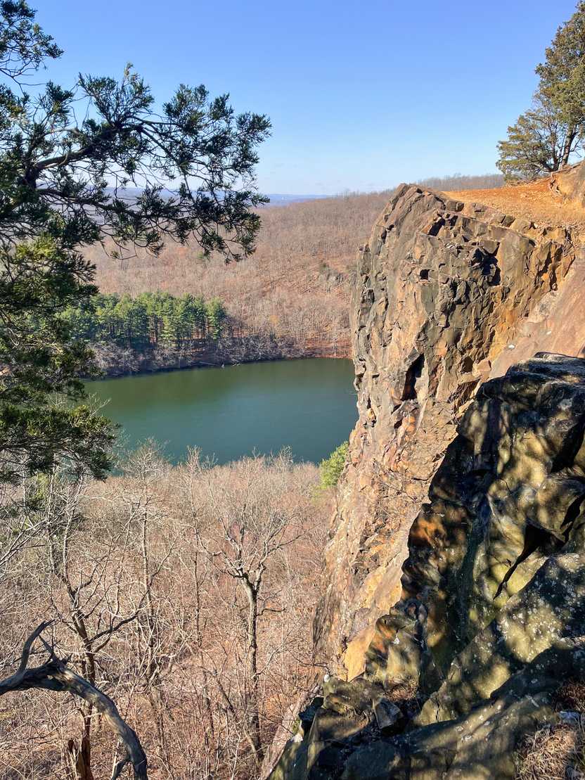 Taken from the top of Chauncey Peak, a rocky cliff stands tall above a lake.