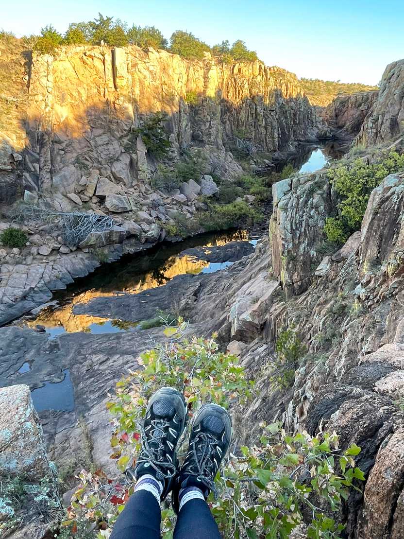 A photo of Lydia's feet wearing Merrell hiking shoes. In the background is a small canyon in Wichita Falls, Oklahoma. A photo of Lydia's feet wearing Merrell hiking shoes. In the background is a small canyon in Wichita Falls, Oklahoma.