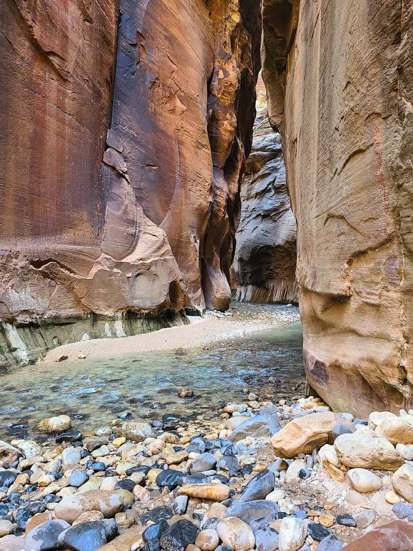 A view of the river flowing between tall canyon walls on The Narrows trail. A view of the river flowing between tall canyon walls on The Narrows trail.