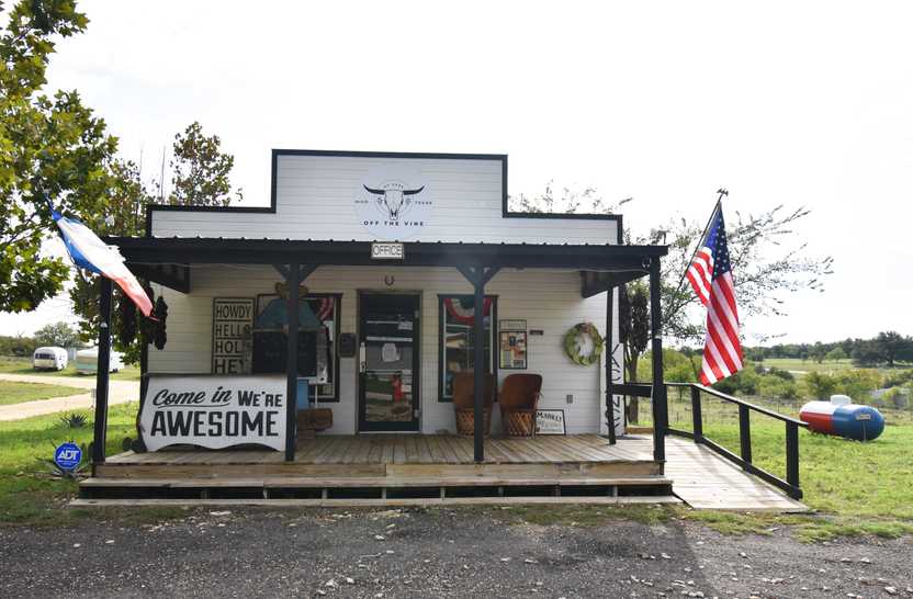 A white, office building for Off the Vine RV Park. A sign outside reads "Come in, We're Awesome"