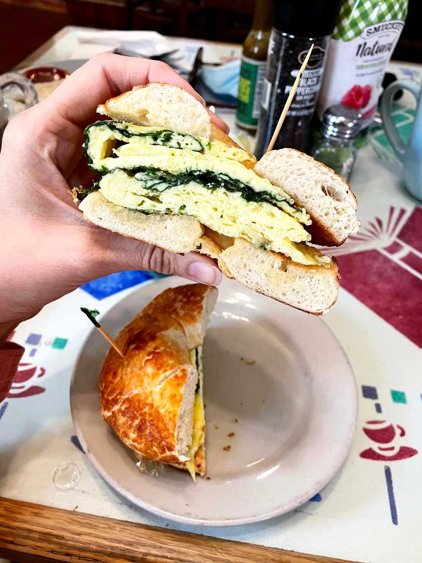 Holding up a bagel breakfast sandwich at the Cathedral Cafe.