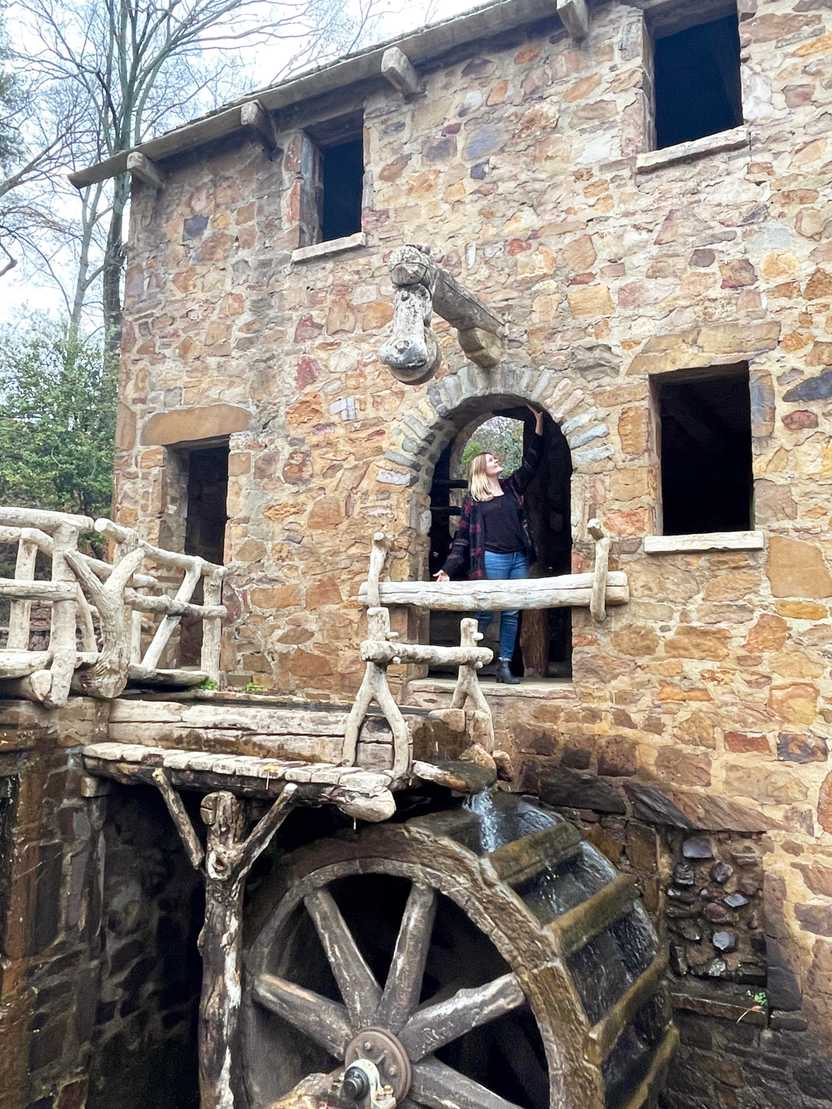 Lydia standing in the archway of the Old Mill. The building is made of tan stones and the water mill is below. Lydia standing in the archway of the Old Mill. The building is made of tan stones and the water mill is below.