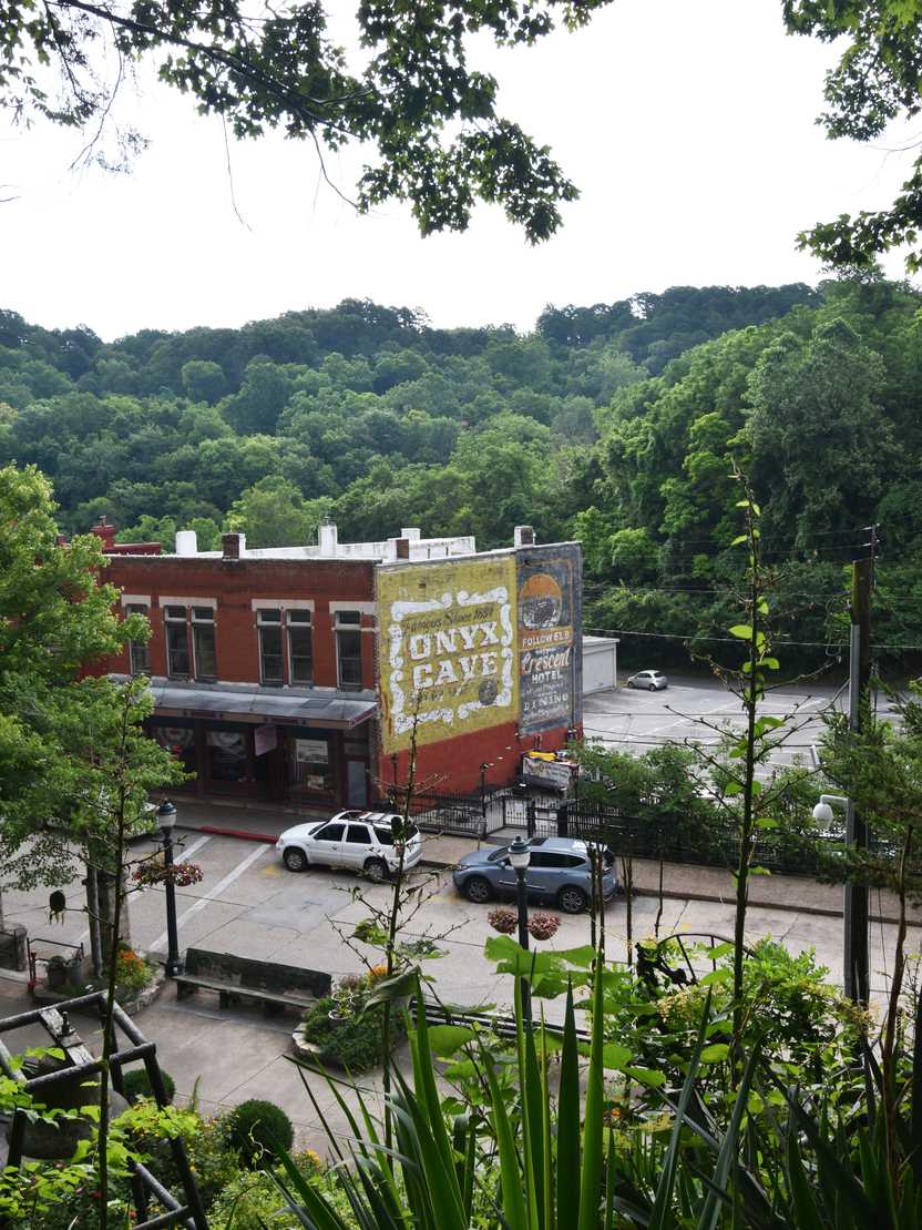 Looking down from a hill at a brick building that has the words 'Onyx Cave' painted on the side.