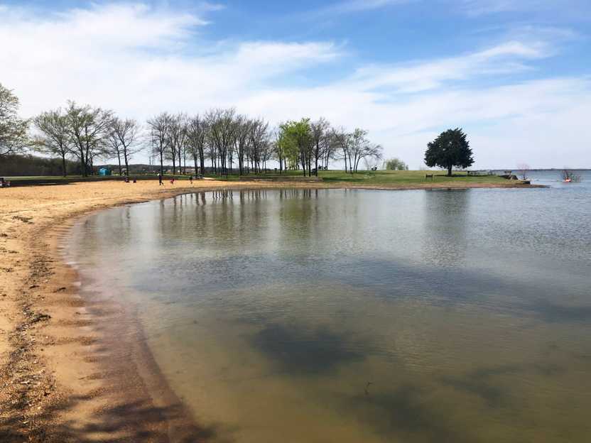 A lake with a small beach area and some trees in the distance.