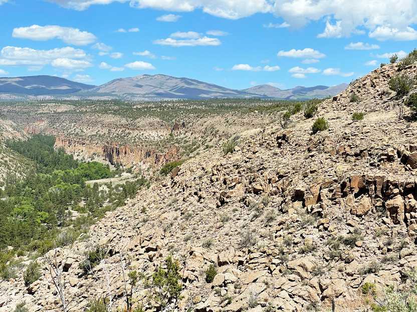 An overlook view of rocks and trees with mountains in the distance.