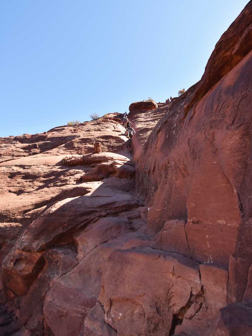 Looking up at a rock scramble on the Cathedral Rock trail. You climb up an orange rock face and it requires some big steps.