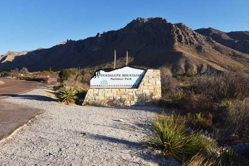 The national park entrance park sign for the Guadalupe Mountains. The sign is light blue with a geometric pattern and a desert plant on the bottom.