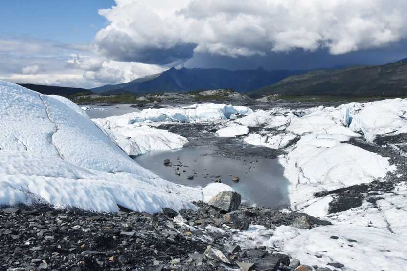A view looking down at Matanuska Glacier. There is a pool of water surrounded by ice.