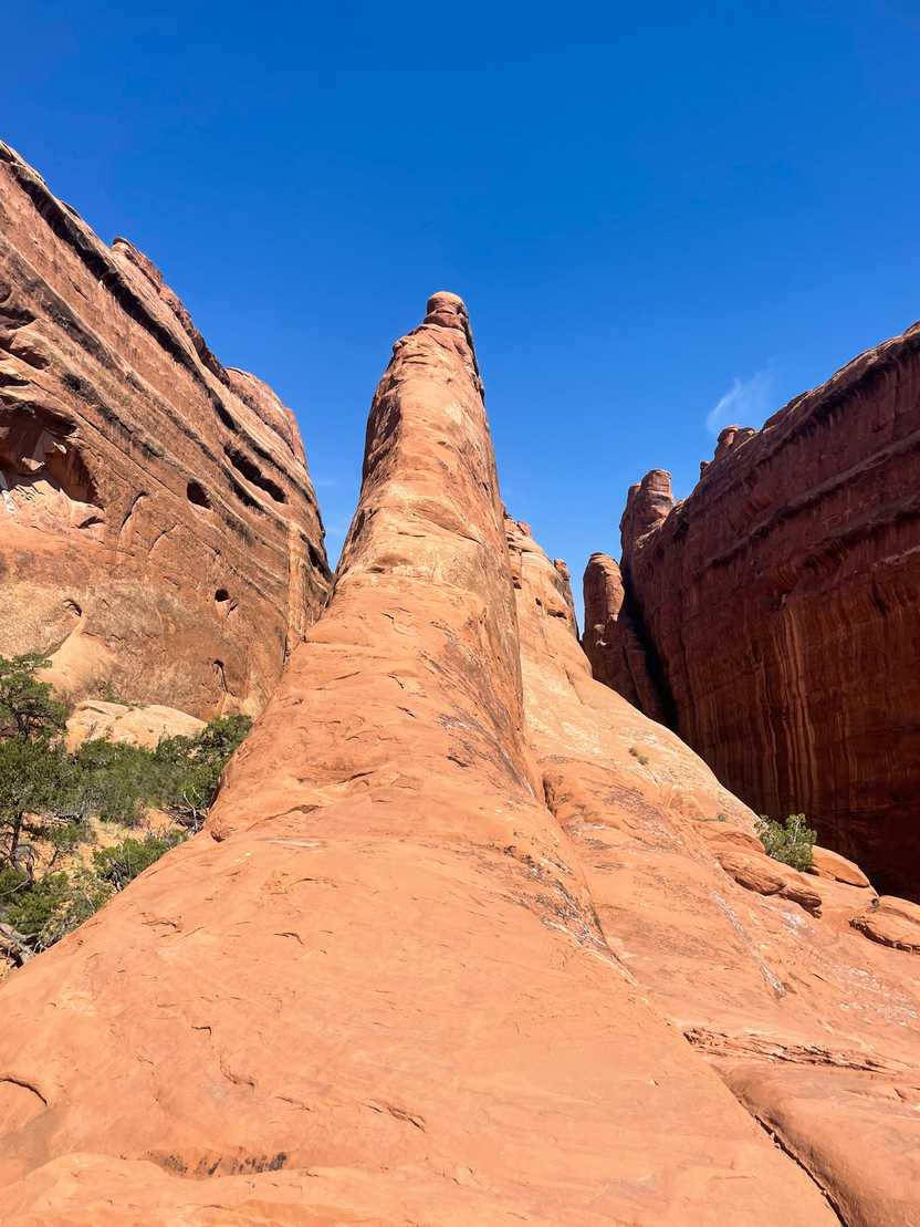 Looking up at an orange rock fin that you have to climb around on the Devil's Garden trail