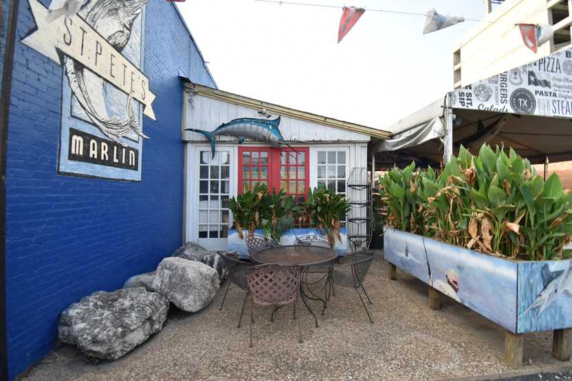 The patio space at St Pete's. There are some planters with greenery and a swordfish hanging on the wall.