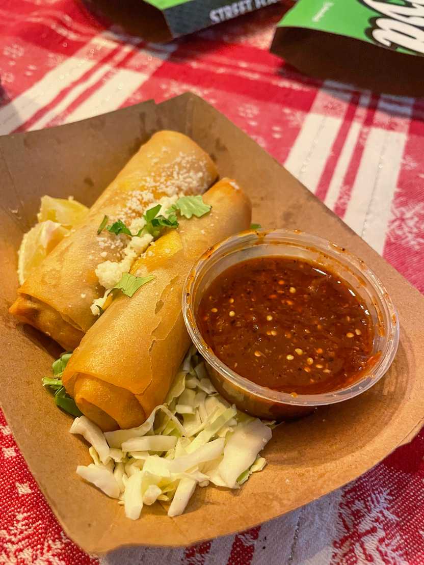 A close up view of egg rolls and a red sauce.