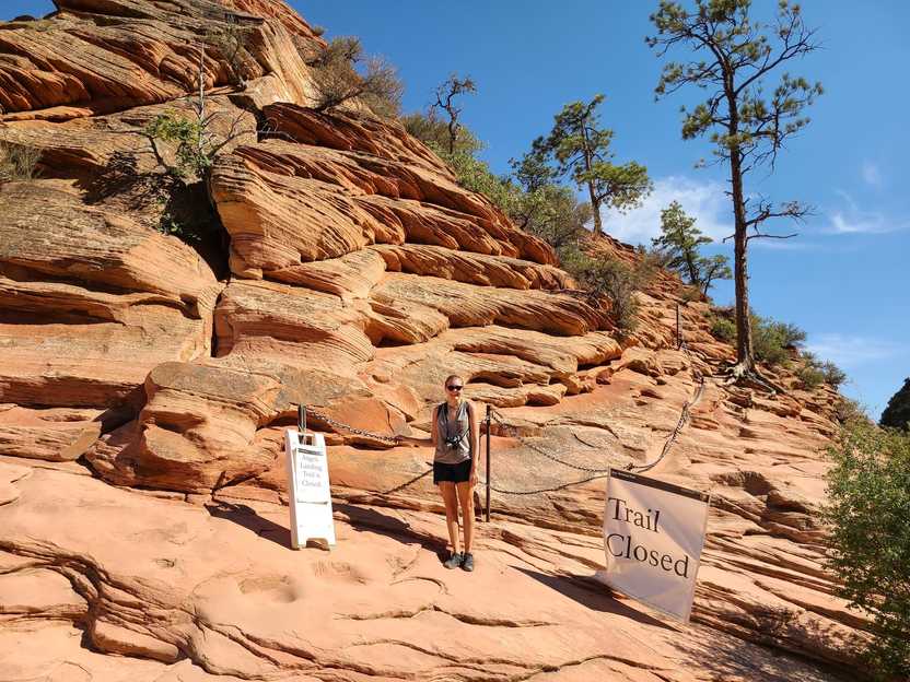 Lydia standing in front of a chain and a sign that reads "Trail Closed"