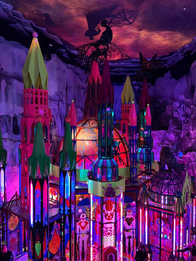 A castle-like building inside of Meow Wolf. The room is mostly pink with a cloudy pink sky above.