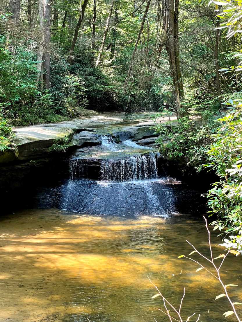 A small waterfall that stair steps down into a river.