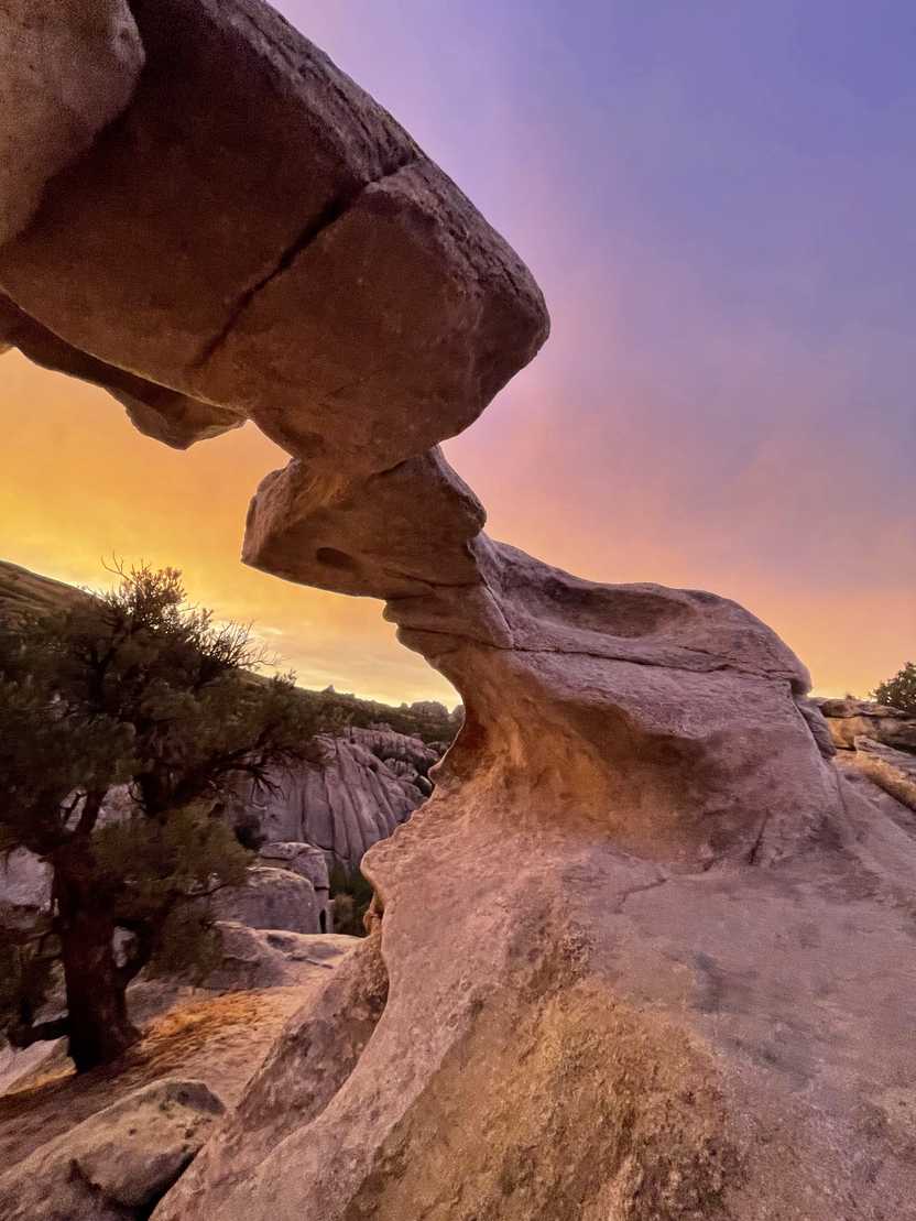 A thin arch with a yellow and purple sunset sky. A thin arch with a yellow and purple sunset sky.