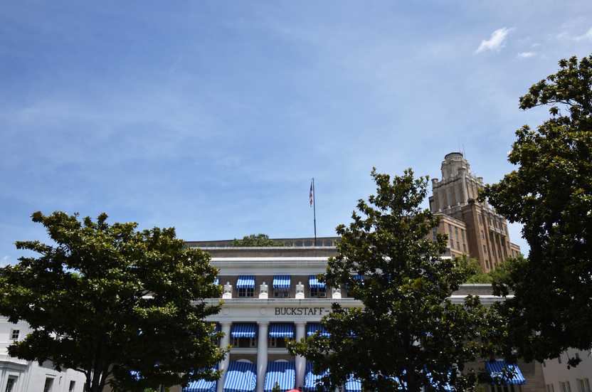 A exterior of Buckstaff Bathhouse. There are some trees in front and awnings with blue and white stripes.