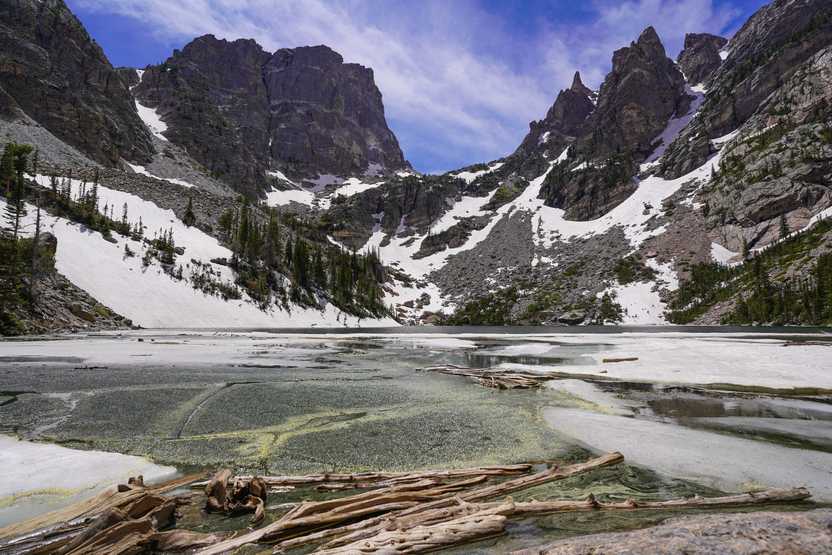 A view of Emerald Lake when it is partially frozen. Jagged, mountain peaks are located directly across the lake.