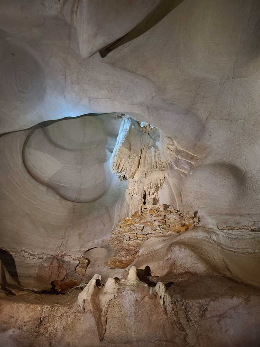 Looking up at stalactites inside of Longhorn Caverns. The interior of the cave is an off white color.