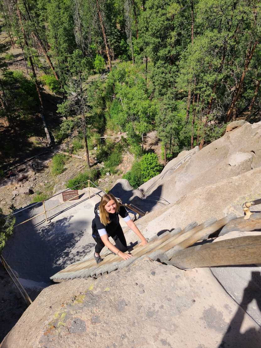 Lydia climbing a ladder on a trail in Bandelier National Monument in New Mexico.