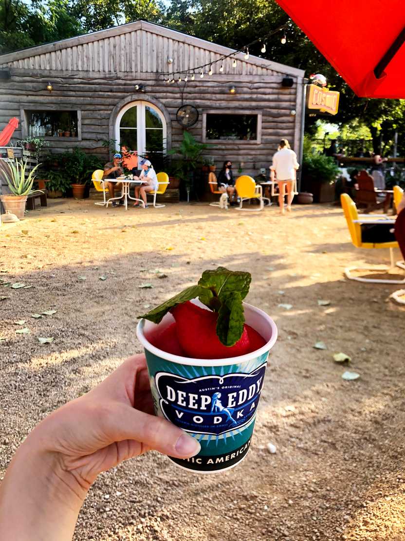 Holding up a slushie cocktail from Cosmic Coffee + Beer