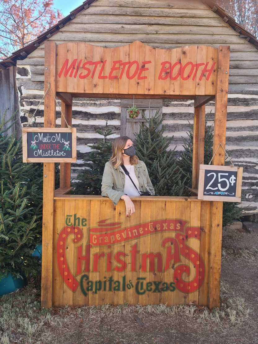 Lydia standing in a booth labeled "Mistletoe Booth" with a 25 cents price tag. Lydia standing in a booth labeled "Mistletoe Booth" with a 25 cents price tag.