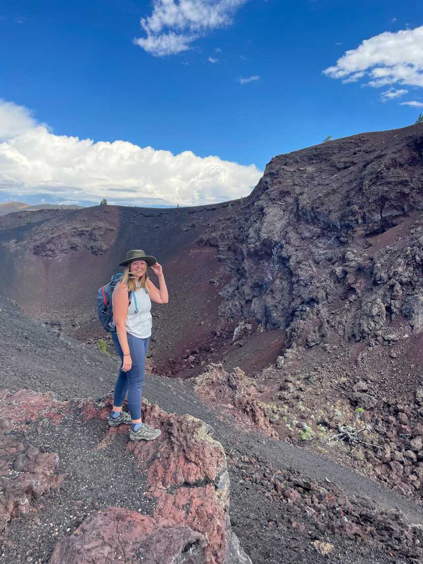 Lydia standing in an area of red and black rocks at Craters of the Moon National Monument. Lydia standing in an area of red and black rocks at Craters of the Moon National Monument.