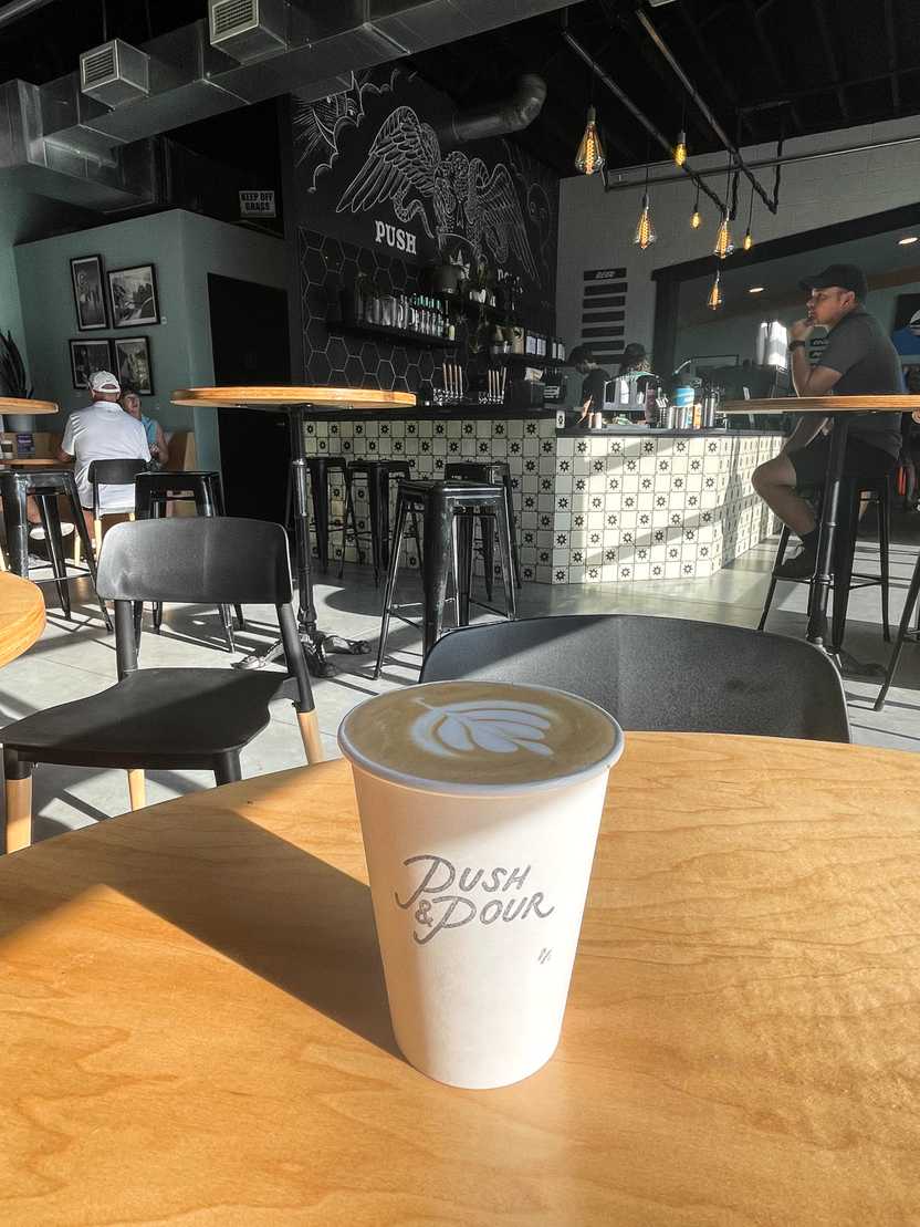 A coffee with latte art inside of Push & Pour.