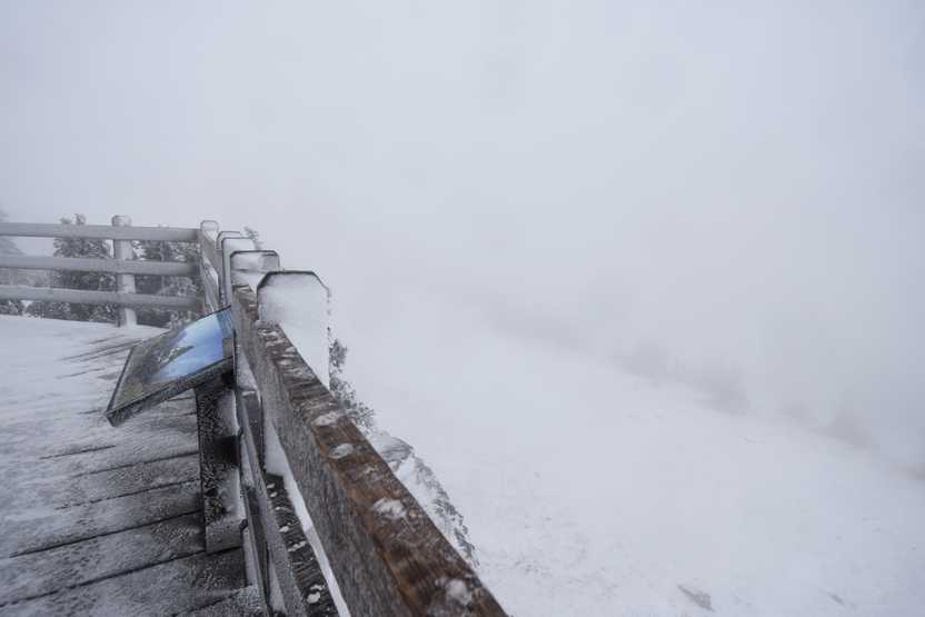 A wooden fence with a view that is completely covered in fog.